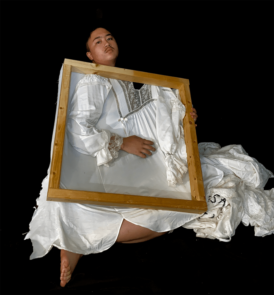 Male student wearing white dress holding frame