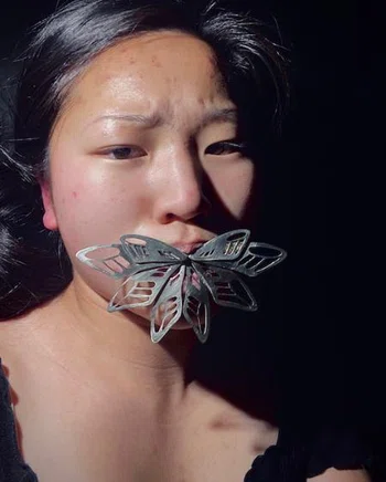 Metal butterfly wings emerging from girl's mouth
